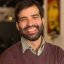 Closeup of happy joyful bearded guy posing indoors. Young man wearing casual, looking at camera and smiling. Male portrait concept